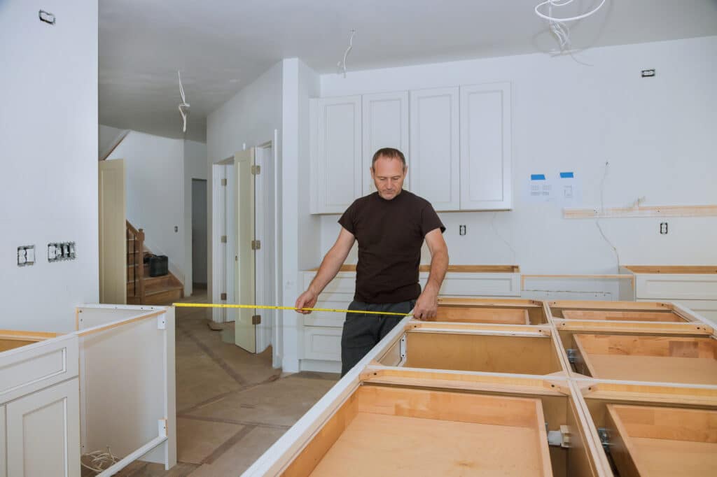 Carpenter takes measurement during kitchen installation.