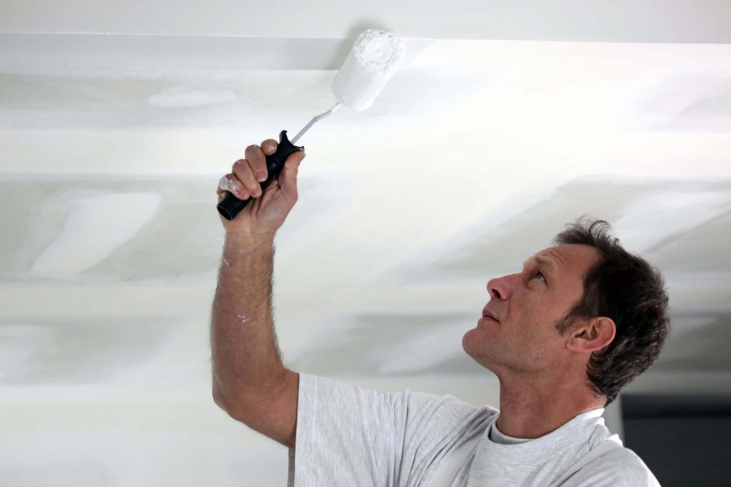 Professional painter rolling the ceiling.